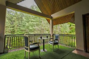 a porch with two chairs and a table on a balcony at The Woodlane Cottage in Kūfrī
