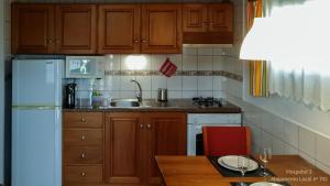 eine Küche mit Holzschränken und einem weißen Kühlschrank in der Unterkunft Hospetur 2 in Horta