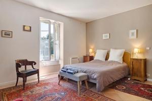 a bedroom with a bed and a chair and a window at La maison de Léandre - Medoc in Saint-Seurin-de-Cadourne +24 photos