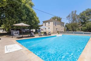 a swimming pool with chairs and umbrellas next to a house at La maison de Léandre - Medoc in Saint-Seurin-de-Cadourne