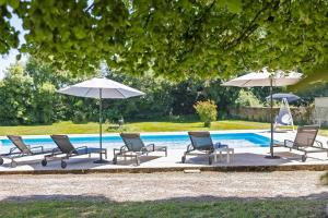 a group of chairs and umbrellas next to a pool at La maison de Léandre - Medoc in Saint-Seurin-de-Cadourne
