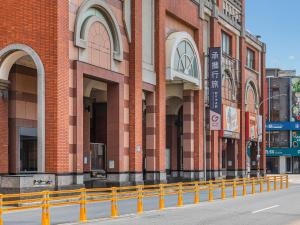 a red brick building with a yellow fence in front of it at Guide Hotel Hsinchu Zhongyang in Hsinchu City