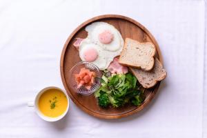 a plate of food with eggs and toast and a cup of soup at Hotel FLOW in Misato