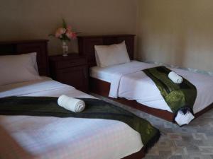 a bedroom with two beds and a vase with flowers at Phetphaylin Hotel in Ban Talai