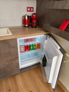 an open refrigerator in a kitchen with soda cans at Apartmán Ateliér in Bílé Vchynice