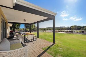 a covered patio with a table and chairs and a field at Rileystone in Margaret River Town