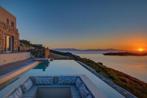 a pool with a view of the ocean at sunset at La VILLA DELLE TORRI in Ermoupoli