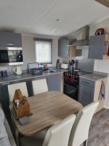 a kitchen with a wooden table and white chairs at Iris - D6 in Eyemouth
