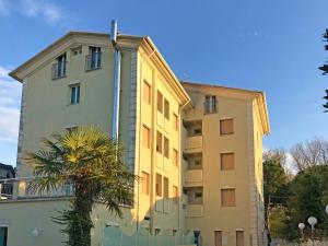 a yellow building with a palm tree in front of it at Hotel San Carlo in Cesenatico