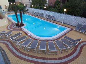 a swimming pool with lounge chairs and a palm tree at Hotel San Carlo in Cesenatico