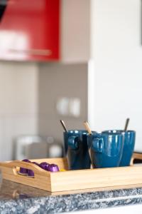 a wooden cutting board with two blue cups on a counter at Warm cocoon - parking included in Asnières-sur-Seine
