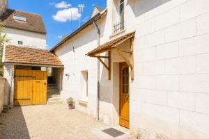 a white brick building with wooden doors on it at Cacatoès in Saint-Aignan