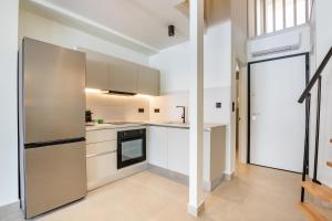 a kitchen with white cabinets and a stainless steel refrigerator at Ble city in Karpathos