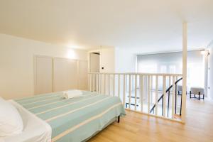 a white bedroom with a bed and a staircase at Ble city in Karpathos