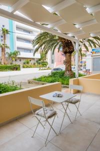 a table and chairs on a patio with palm trees at Ble city in Karpathos
