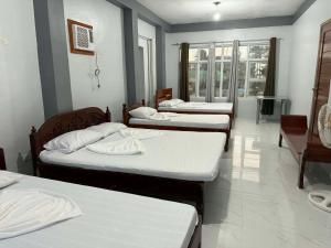 a group of four beds in a room at Yasmin's Transient House in Pagudpud