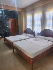 two beds sitting in a room with windows at Yasmin's Transient House in Pagudpud