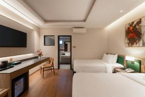 a hotel room with two beds and a desk at NiK Hotel Thi Sach in Ho Chi Minh City