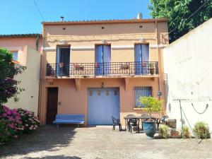 a house with a balcony and a table and a bench at Grande maison familiale proche mer in Elne