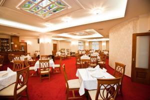 een eetkamer met tafels en stoelen en een plafond bij Hotel Maxim in Oradea