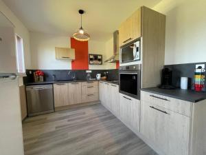 a large kitchen with wooden cabinets and stainless steel appliances at Gîte Le Mailloux - Maison calme à 15 min du Pal in Saligny-sur-Roudon