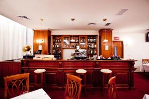 bar w restauracji z drewnianymi szafkami i stołkami w obiekcie Hotel Maxim w mieście Oradea