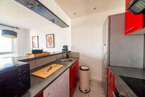 a kitchen with red cabinets and a stainless steel refrigerator at Warm cocoon - parking included in Asnières-sur-Seine +20 photos