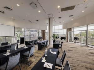 a restaurant with black tables and chairs and windows at ibis Sydney Olympic Park in Sydney