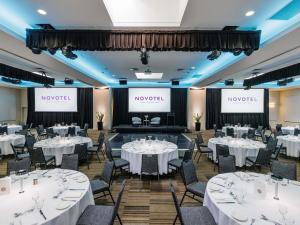 a banquet hall with white tables and chairs and two screens at ibis Sydney Olympic Park in Sydney