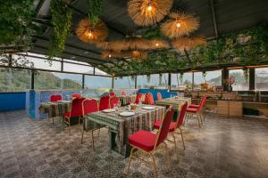 a restaurant with tables and red chairs and windows at Glow Sapa Hotel in Sapa