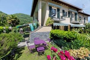 a house with purple chairs and flowers in the yard at Casa Ezia in Porlezza