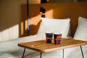two coffee cups sitting on a wooden tray on a bed at Scandic Go, Kungsgatan 14 in Jönköping