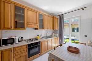 a kitchen with wooden cabinets and a table with a microwave at Casa Ezia in Porlezza