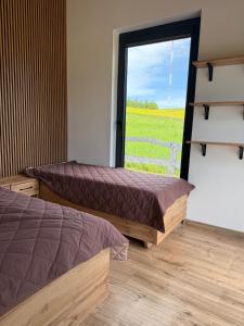 two beds in a room with a large window at Oaza Żuraw in Miłki