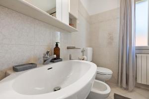 a white bathroom with a tub and a toilet at Casa Ezia in Porlezza +25 photos