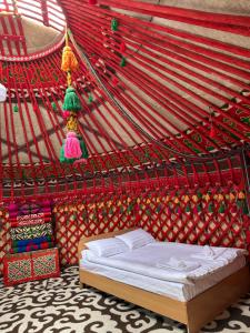 a bedroom with a bed in a red tent at Marjan Guest House in Bokonbayevo