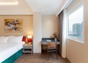 a hotel room with a bed and a desk and a window at NiK Hotel Thi Sach in Ho Chi Minh City