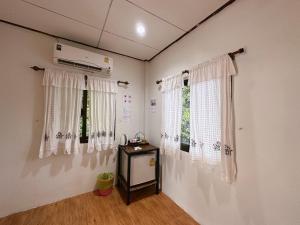 a room with white curtains and a table and two windows at Khao Sok Jungle Huts Resort in Khao Sok National Park +185 photos
