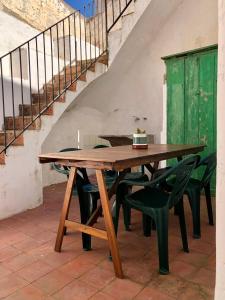 a wooden table with green chairs and a staircase at Casa l'àvia - Sant Pol de Mar in San Pol de Mar