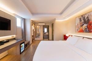 a bedroom with a large bed and a flat screen tv at NiK Hotel Thi Sach in Ho Chi Minh City