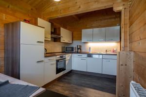a kitchen with white appliances and wooden walls at Waldsiedlung - Haus 13 in Großkoschen