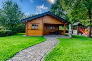 a small wooden cabin with a playground in a yard at Waldsiedlung - Haus 13 in Großkoschen