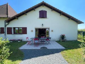 a white house with red chairs and a table at Gîte Le Mailloux - Maison calme à 15 min du Pal in Saligny-sur-Roudon