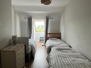 a bedroom with two beds and a dresser and a window at Large Holiday Apartment Enniscrone in Enniscrone