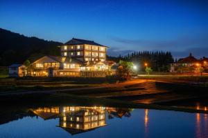 a large building at night with a reflection in the water at 六日町温泉 龍氣 in Minami Uonuma