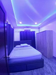 a bedroom with a bed in a room with purple lights at Rams home in Moalboal +1 photo