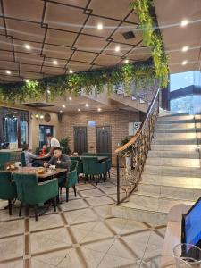 a restaurant with people sitting at tables and a staircase at Hotel Mardin in Almaty