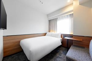 a bedroom with a white bed and a window at Sotetsu Grand Fresa Osaka-Namba in Osaka