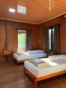 a bedroom with two beds and a guitar at Dico Surf Point- Surf Lodge in Simeulue in Lasikin