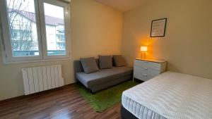 a bedroom with a bed and a couch and a window at Le Pegan - Appartement 2 chambres proche du centre de Ferney et de Palexpo in Ferney-Voltaire
